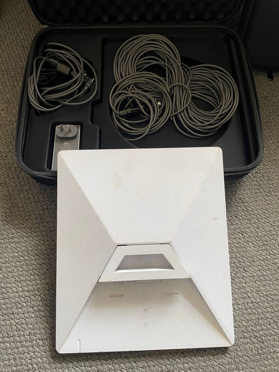 Both hire kit cables coiled in the case, the mains adapter, and the dish turned over on its kickstand